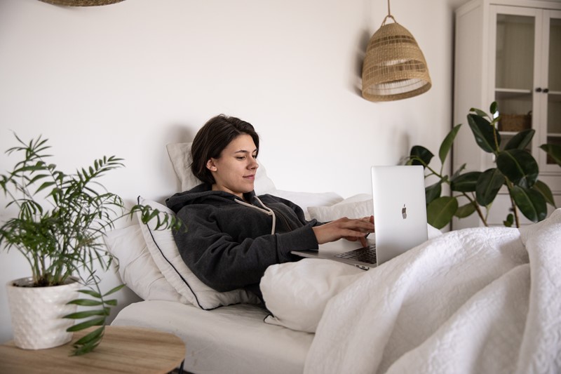 Frau mit Laptop im Bett macht kurze Pause