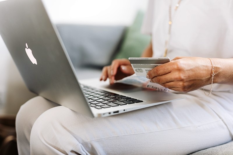 Frau bezahlt mit Karte online am Laptop