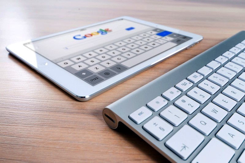 Eine Tastatur liegt vor einem Tablet mit der geöffneten Google Website.