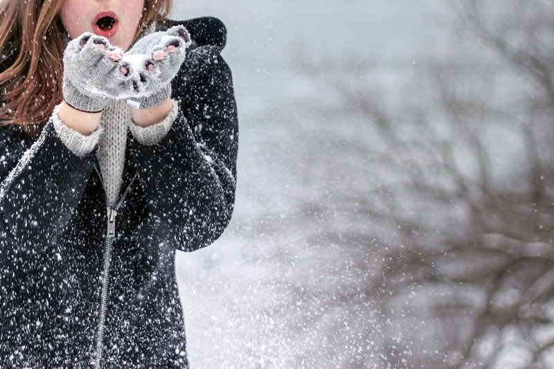 Frau bläst Schnee aus ihren Händen