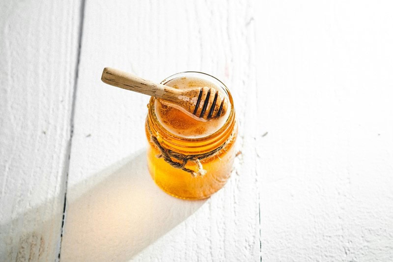 Ein Glas mit Honig und einem Honiglöffel