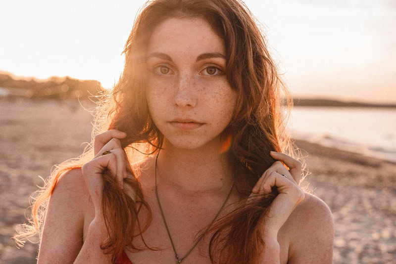 Frau am Strand fasst sich in die Haare