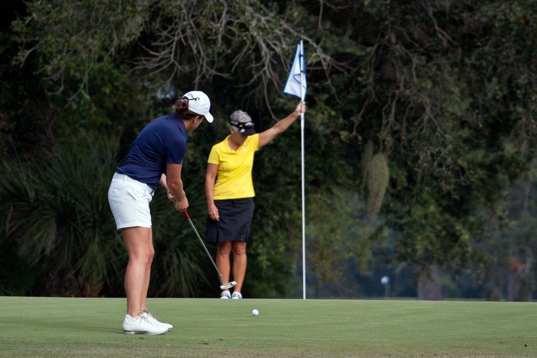 Golferin nutzt Putter, um Ball in Loch zu versenken.